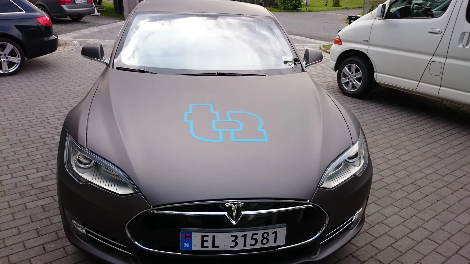 Tesla Model S med matt svart wrap og cyan t12-logo