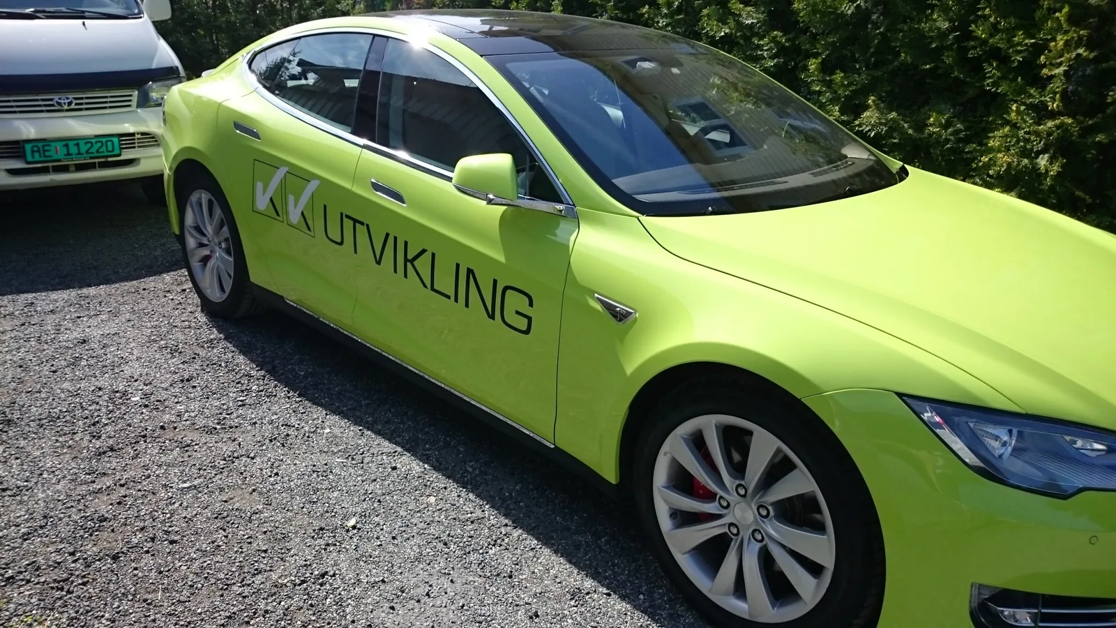 Limegrønn Tesla Model S med VK Utvikling-logo